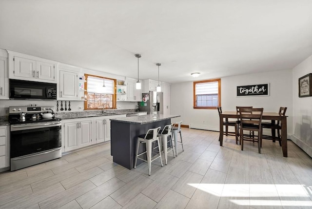 kitchen featuring a breakfast bar area, decorative light fixtures, appliances with stainless steel finishes, a kitchen island, and white cabinets