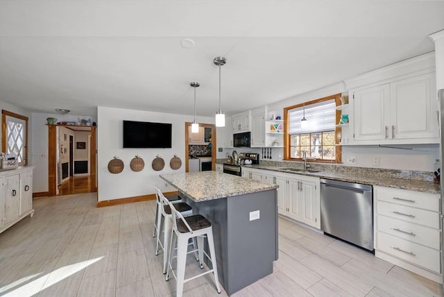 kitchen with a kitchen island, a breakfast bar, white cabinetry, sink, and stainless steel appliances