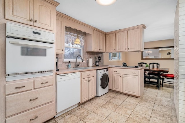 kitchen featuring a peninsula, white appliances, a sink, light countertops, and washer / clothes dryer