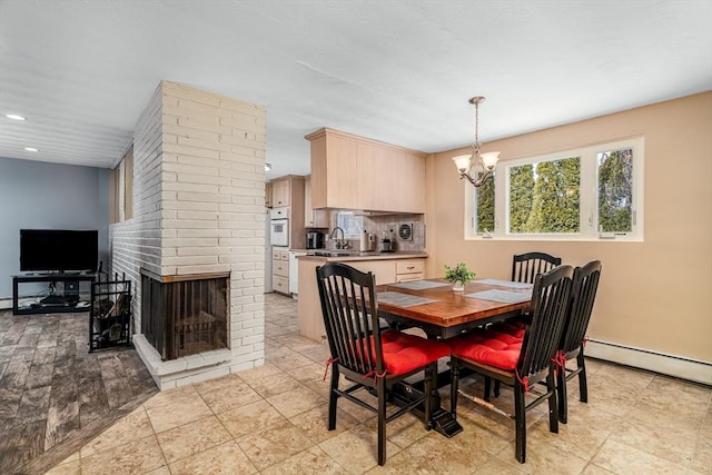 dining room featuring a brick fireplace, a chandelier, a baseboard heating unit, and recessed lighting