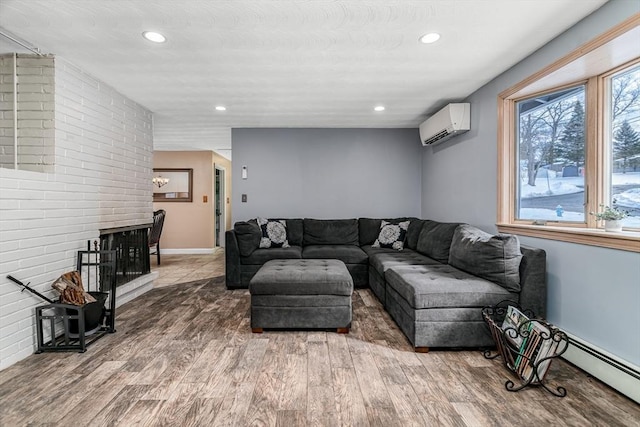 living room with a wall unit AC, recessed lighting, a baseboard heating unit, wood finished floors, and a brick fireplace