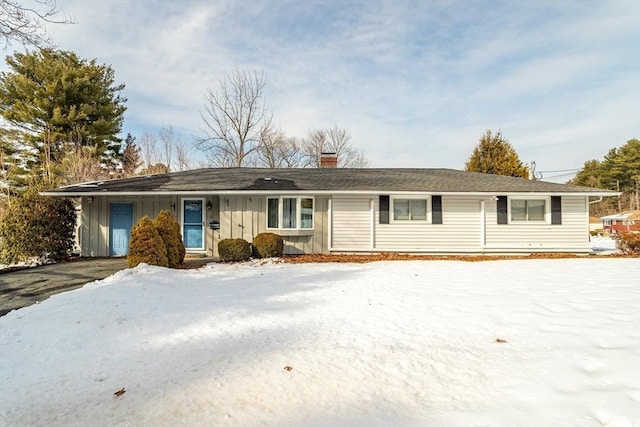 ranch-style home with board and batten siding and a chimney