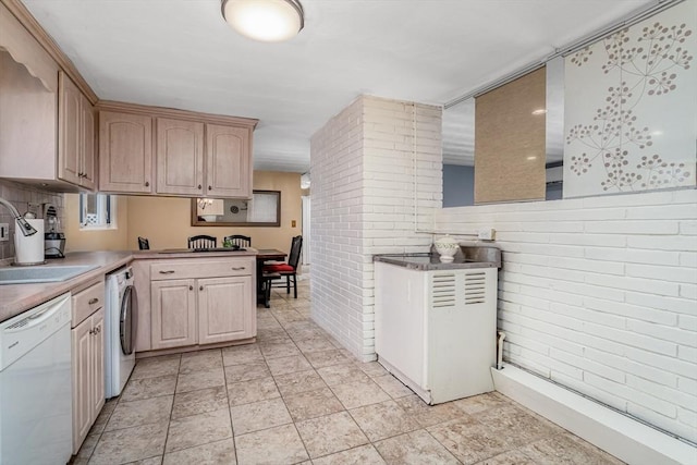 kitchen with washer / clothes dryer, a peninsula, white dishwasher, light brown cabinets, and a sink