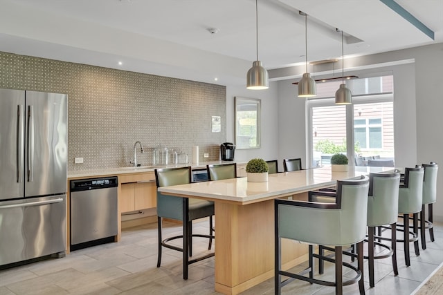 kitchen with a kitchen breakfast bar, tasteful backsplash, stainless steel appliances, pendant lighting, and a kitchen island