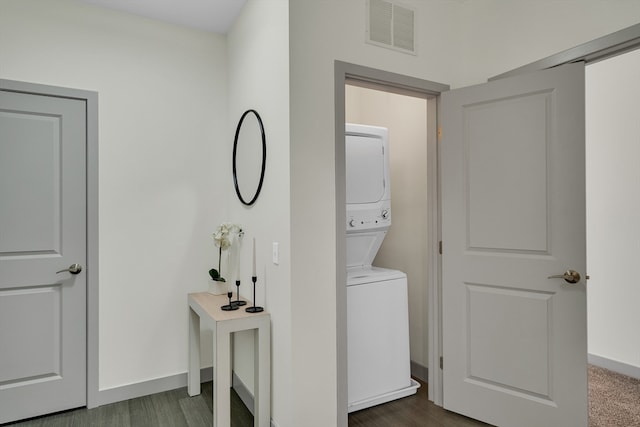 clothes washing area with dark wood-type flooring and stacked washer and clothes dryer