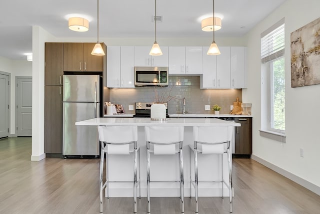 kitchen featuring stainless steel appliances, light hardwood / wood-style flooring, and white cabinets