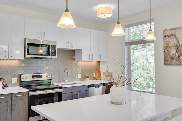 kitchen featuring appliances with stainless steel finishes, white cabinets, sink, and backsplash