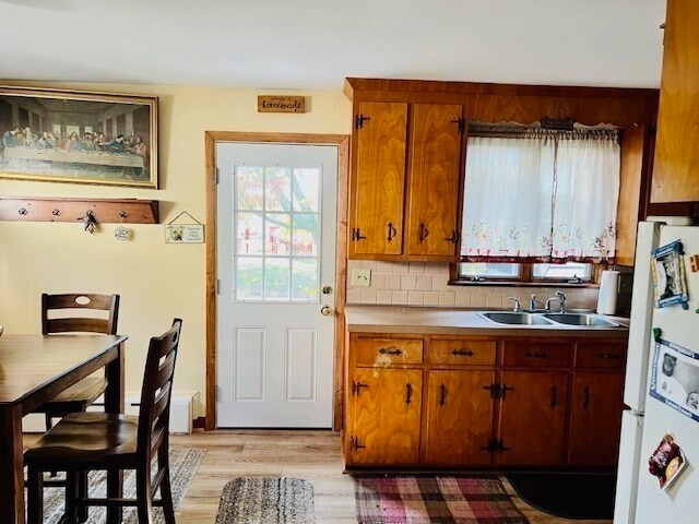 kitchen featuring sink, backsplash, light hardwood / wood-style flooring, and white refrigerator