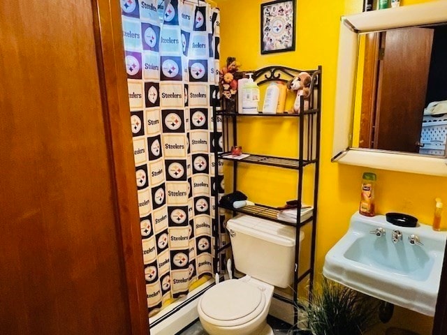 bathroom with sink, toilet, a baseboard heating unit, and curtained shower