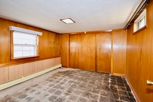 spare room featuring baseboard heating and wooden walls