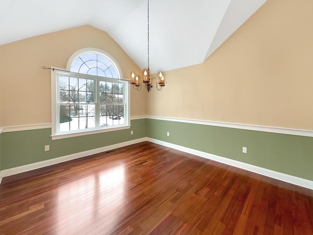 empty room featuring an inviting chandelier, wood-type flooring, and vaulted ceiling