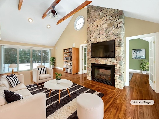 living room featuring ceiling fan, high vaulted ceiling, dark hardwood / wood-style floors, a fireplace, and beamed ceiling