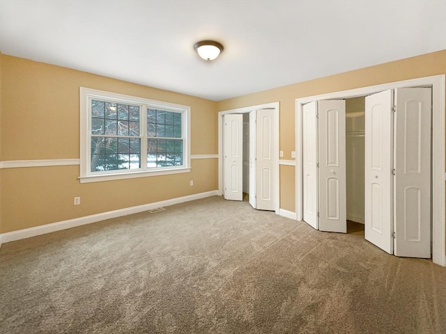 unfurnished bedroom featuring carpet flooring and two closets