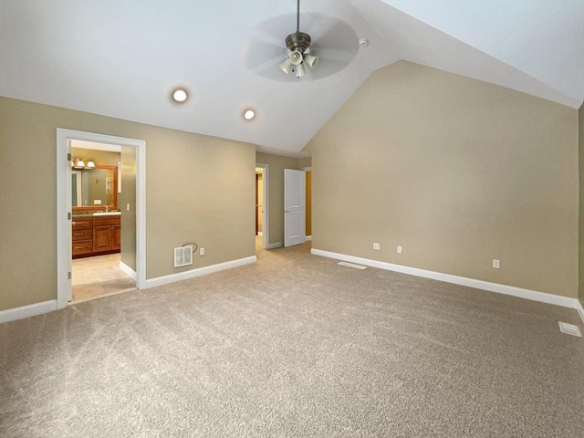 unfurnished bedroom with ceiling fan, light colored carpet, connected bathroom, and vaulted ceiling