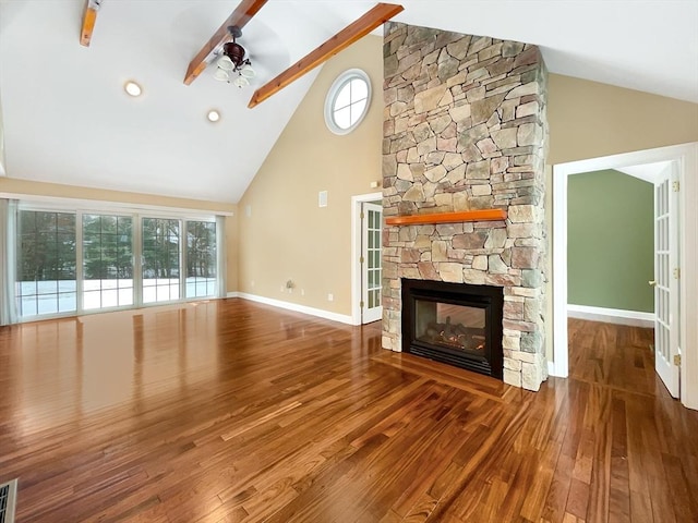 unfurnished living room featuring a stone fireplace, wood-type flooring, high vaulted ceiling, ceiling fan, and beam ceiling