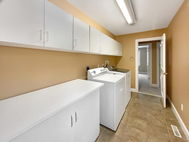 clothes washing area featuring cabinets and washer and clothes dryer