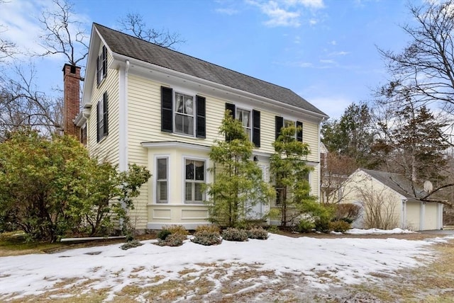 view of front of home featuring a chimney and an outbuilding