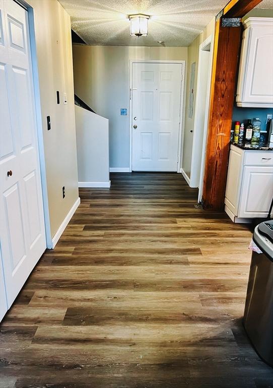 interior space featuring a textured ceiling, wood finished floors, and baseboards