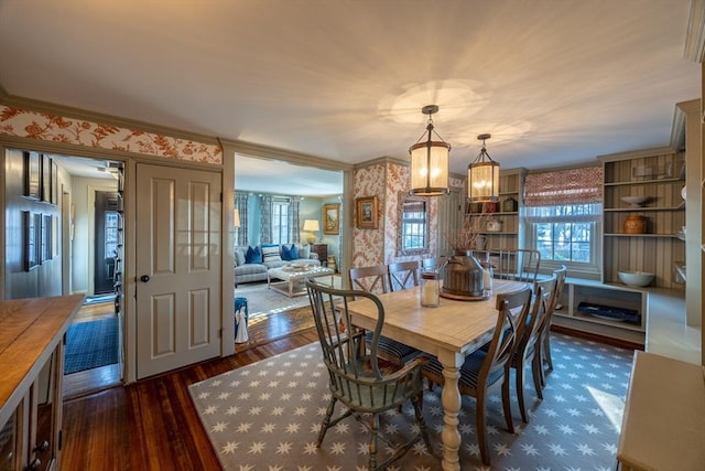 dining area featuring dark hardwood / wood-style flooring, crown molding, and a notable chandelier