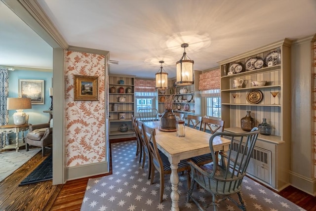 dining room featuring dark wood-type flooring, ornamental molding, and an inviting chandelier