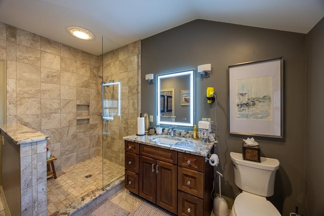 bathroom featuring toilet, a tile shower, tile patterned flooring, lofted ceiling, and vanity