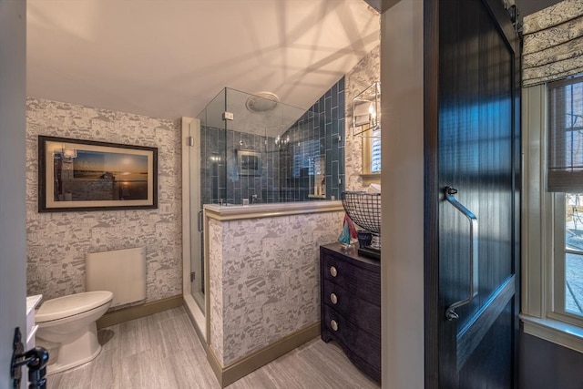 bathroom featuring hardwood / wood-style floors, toilet, a shower with door, and lofted ceiling