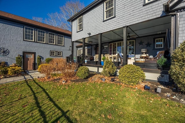 rear view of house featuring covered porch and a yard