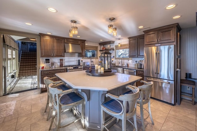 kitchen with hanging light fixtures, decorative backsplash, high end appliances, and a center island