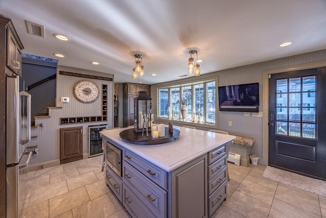 kitchen with stainless steel appliances, a baseboard radiator, beverage cooler, hanging light fixtures, and a center island