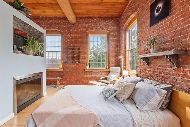 1511 Main St Unit C406, Worcester, MA 01603 - bedroom featuring brick wall, a wood ceiling with exposed beams, wood finished floors, and a glass covered fireplace