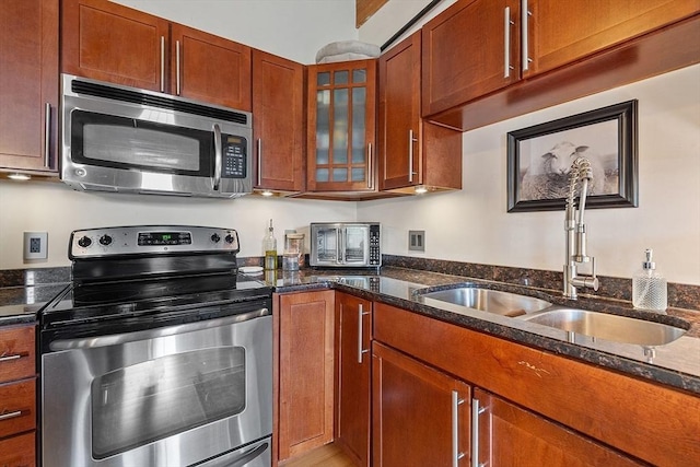1511 Main St Unit C406, Worcester, MA 01603 - kitchen featuring appliances with stainless steel finishes, dark stone countertops, glass insert cabinets, and brown cabinetry