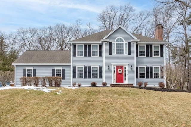 colonial inspired home featuring a chimney, a front lawn, and roof with shingles