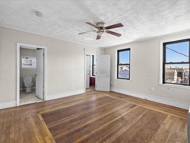 unfurnished bedroom featuring ceiling fan, light wood-type flooring, a textured ceiling, and ensuite bathroom