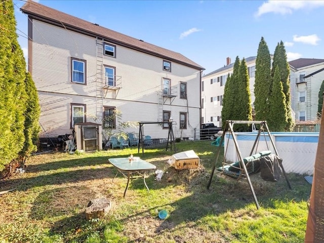 rear view of house featuring a yard and an empty pool