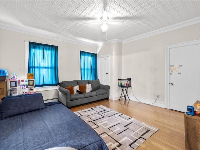 living room featuring ceiling fan, ornamental molding, a baseboard radiator, and wood-type flooring