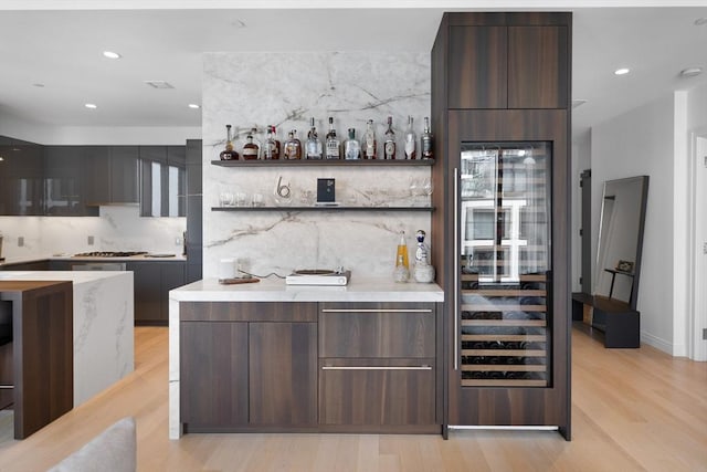 bar featuring decorative backsplash, recessed lighting, a dry bar, and light wood-style flooring