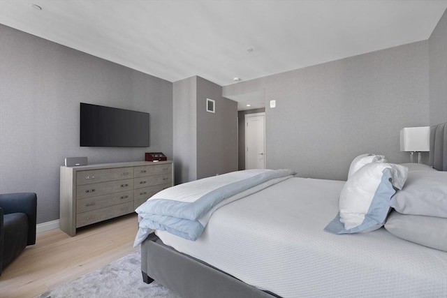 bedroom with baseboards, visible vents, and light wood-style floors