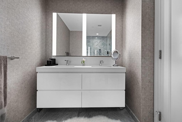 full bathroom featuring double vanity, baseboards, a shower stall, and a sink