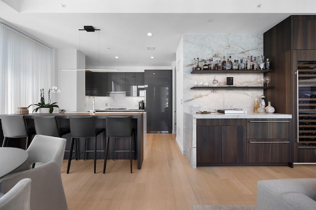 bar with recessed lighting, decorative light fixtures, a bar, and light wood finished floors