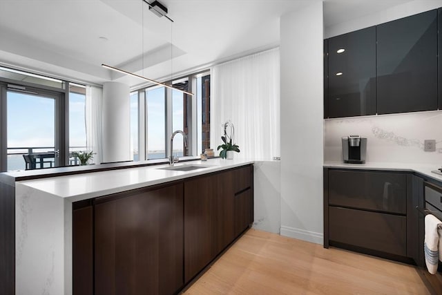 kitchen with a sink, light wood-style floors, light countertops, baseboards, and modern cabinets