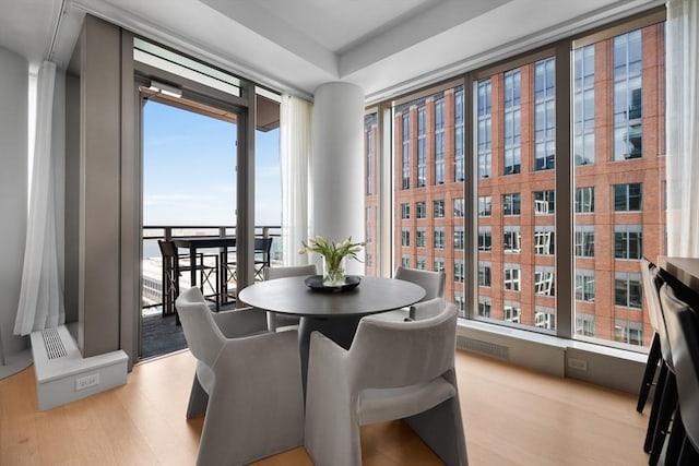 dining room featuring light wood-style floors, floor to ceiling windows, and visible vents