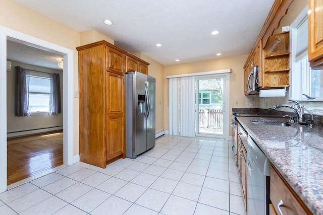 kitchen with open shelves, a sink, a baseboard radiator, stone counters, and appliances with stainless steel finishes