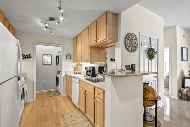 kitchen featuring sink, a kitchen breakfast bar, stacked washer / dryer, white appliances, and light wood-type flooring