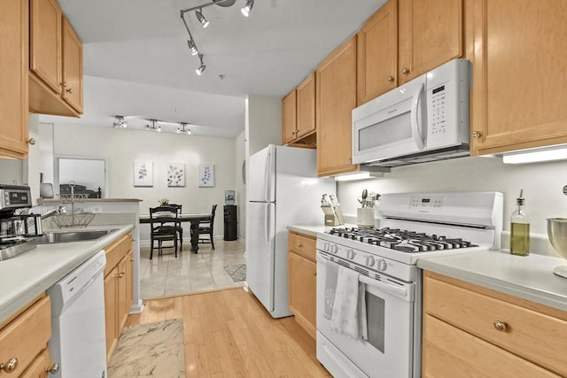 kitchen with light brown cabinetry, light hardwood / wood-style flooring, white appliances, and sink