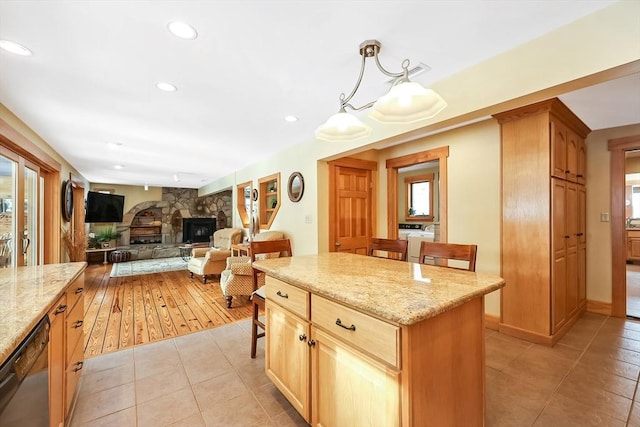 kitchen featuring light stone counters, a center island, pendant lighting, open floor plan, and dishwasher