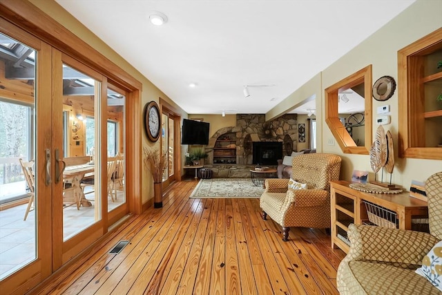 interior space featuring light wood-style floors, visible vents, and a stone fireplace