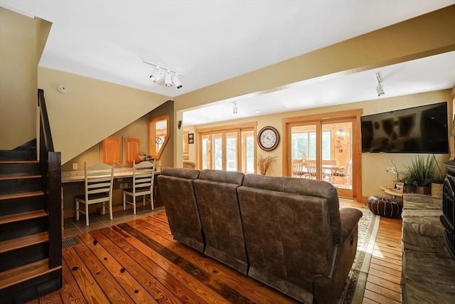 living room featuring lofted ceiling, dark wood-type flooring, stairway, and rail lighting