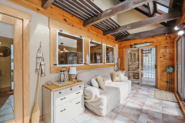 living area featuring light tile patterned floors, beamed ceiling, and wooden walls