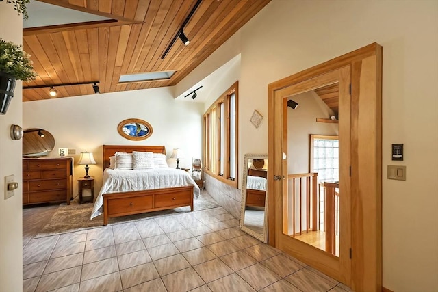 bedroom with wooden ceiling, light tile patterned floors, lofted ceiling with skylight, and track lighting