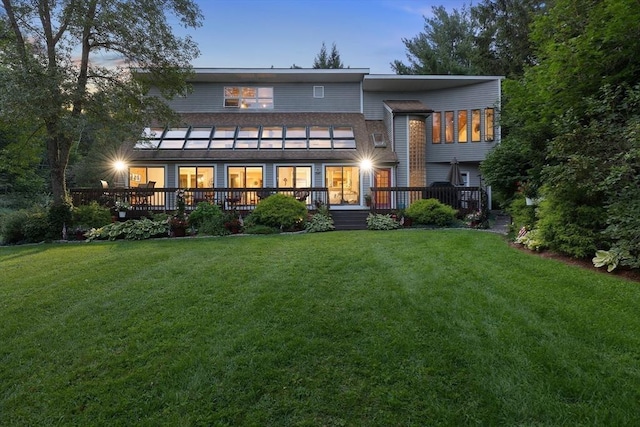 rear view of property featuring a yard and a wooden deck